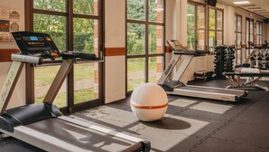 Un gimnasio con cintas de correr, una bicicleta estática y pelotas de ejercicio.