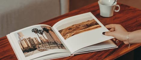 Ein offenes Buch auf einem Holztisch mit einer weißen Tasse und einem Löffel.