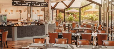 A restaurant with a bar area, multiple tables and chairs, and large windows offering a view of the outdoors.