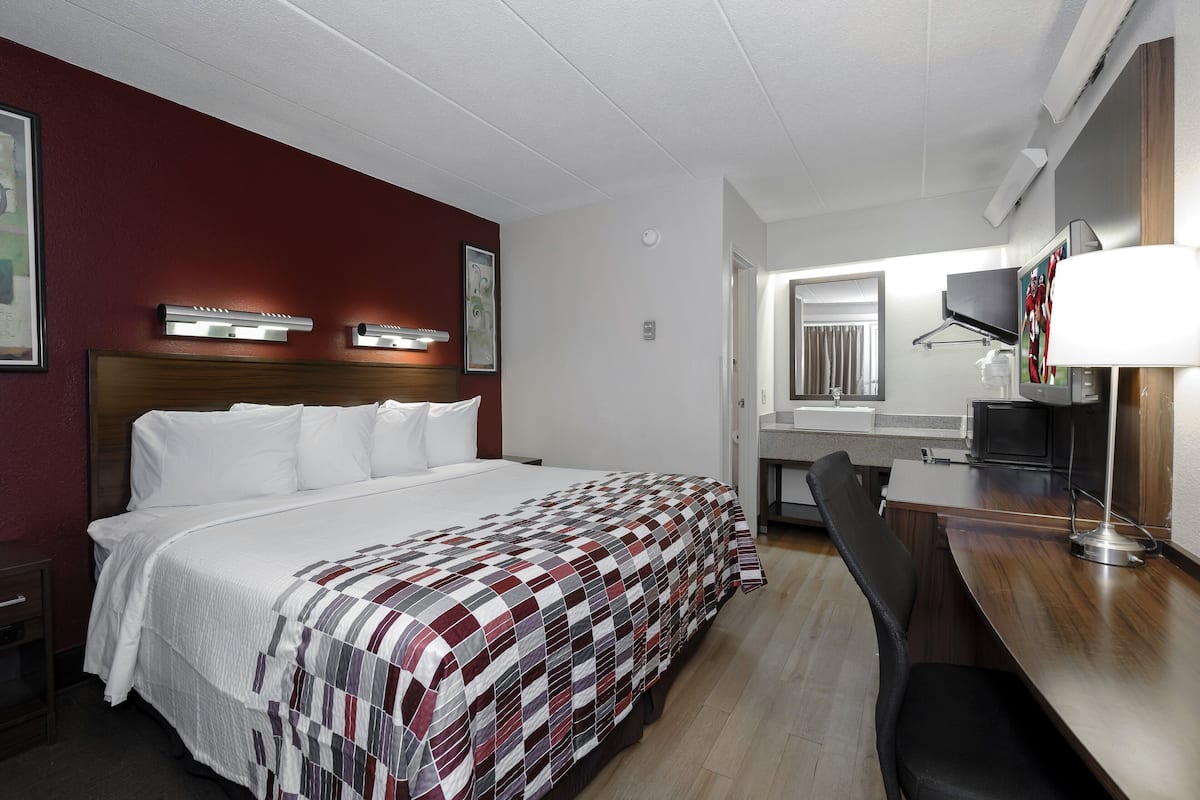 A hotel room with a large bed, a desk, and a mirror.