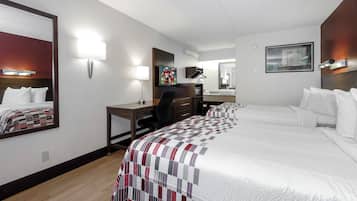 A hotel room with a bed, desk, chair, and a television.