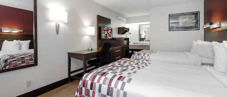 A hotel room with a bed, desk, chair, and a television.