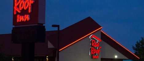 A Red Roof Inn with a prominent neon sign, a red roof, and a modern building facade.