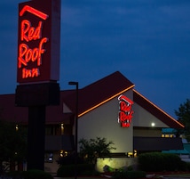 Un hotel Red Roof Inn con un llamativo letrero de neón, techo rojo y fachada de edificio moderna.