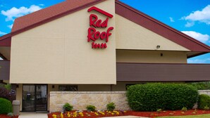 A Red Roof Inn with a stone facade, a red roof, and a clear blue sky.