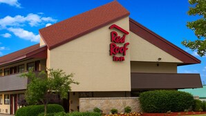 A Red Roof Inn with a red roof, beige walls, and a stone facade.