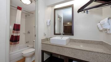 A bathroom with a bathtub, toilet, sink, and a mirror.