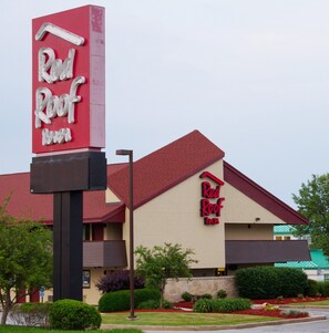 A Red Roof Inn with a prominent red and white sign, a red roof, and a beige facade.