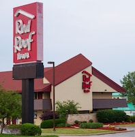 Un hotel Red Roof Inn con un letrero rojo y blanco llamativo, tejado rojo y fachada color beige.
