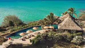 A resort with a pool, lounge chairs, and thatched-roof structures. - Paradise Cove Boutique Hotel - Adults only (Cap Malheureux)