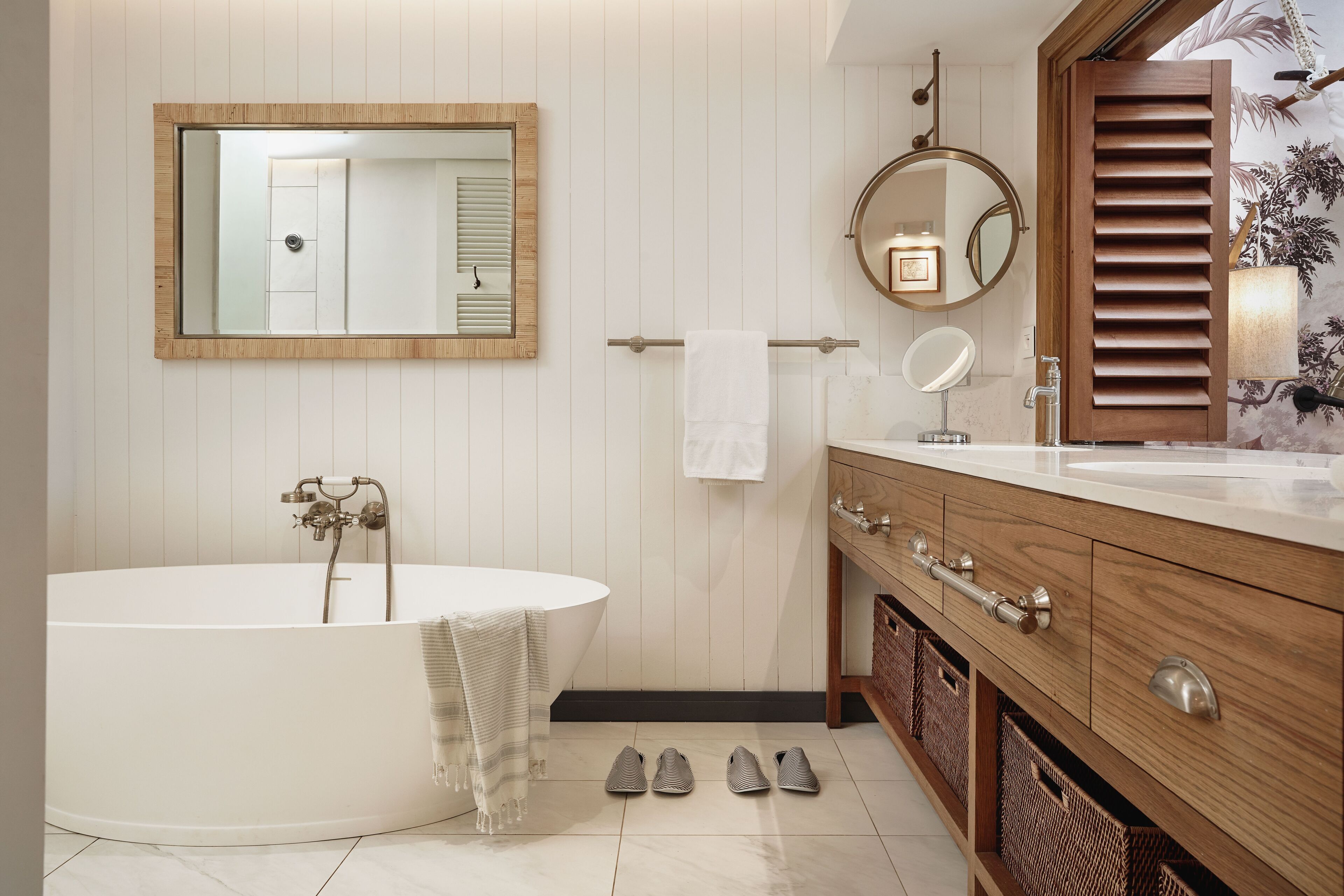 Un baño moderno con una bañera independiente, tocador de madera y un espejo grande.