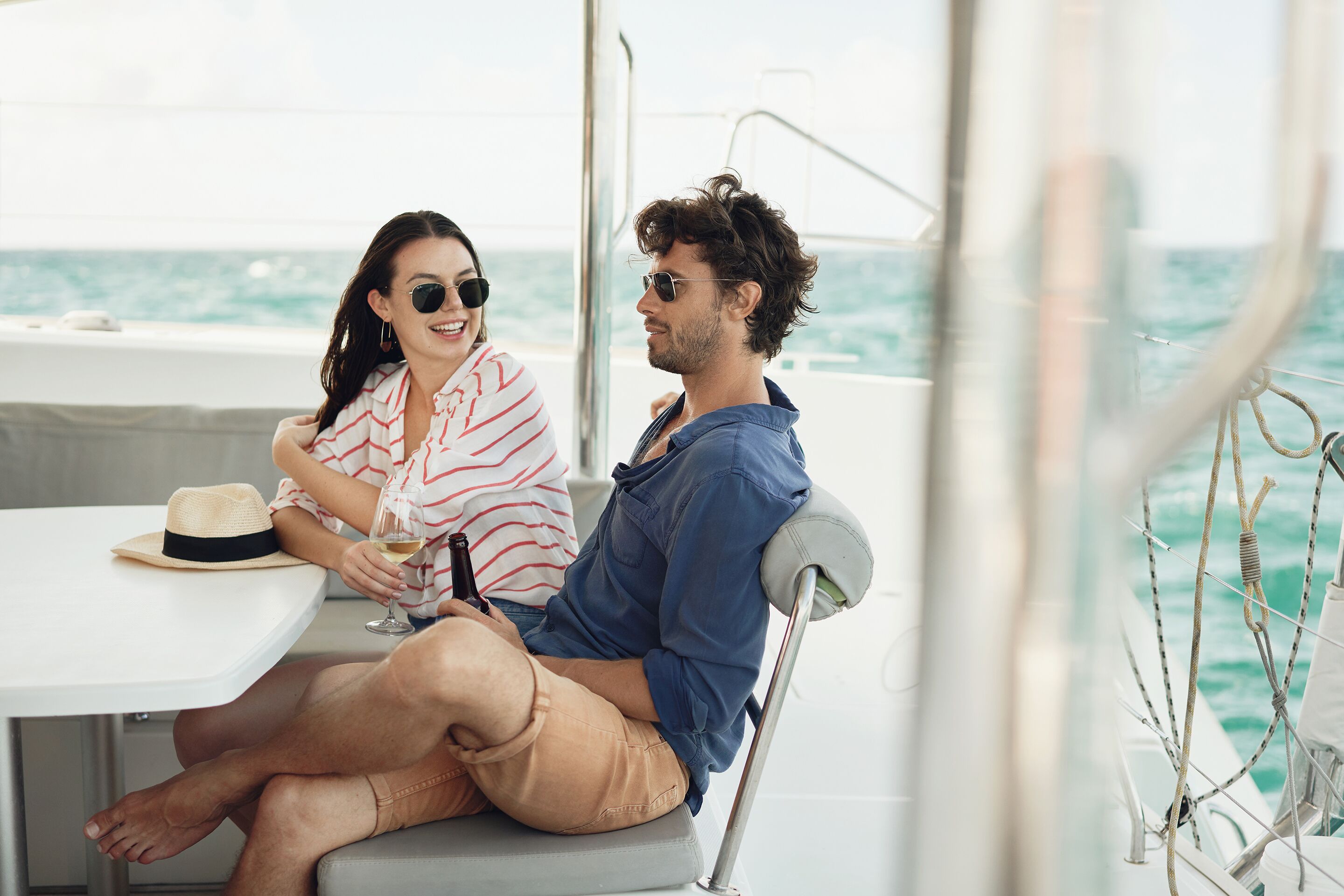 Una pareja sentada en una mesa en un barco, con vista al océano.