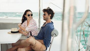 Una pareja sentada en una mesa en un barco, con vista al océano.