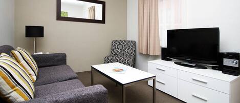 A compact living space with a sofa, a small table, a television, and a cabinet.