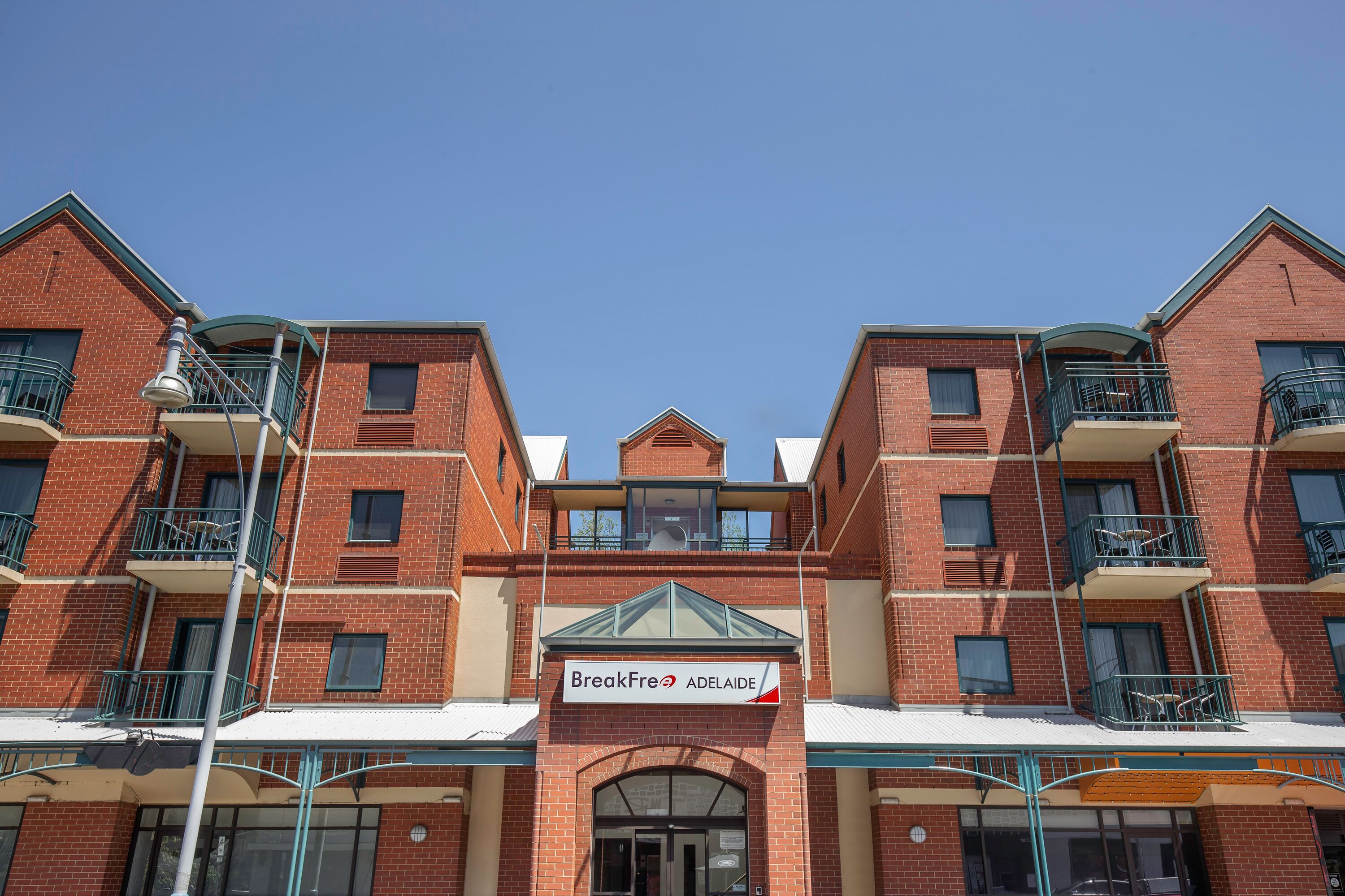 A multi-story brick building with balconies and a sign reading "BreakFree Adelaide".