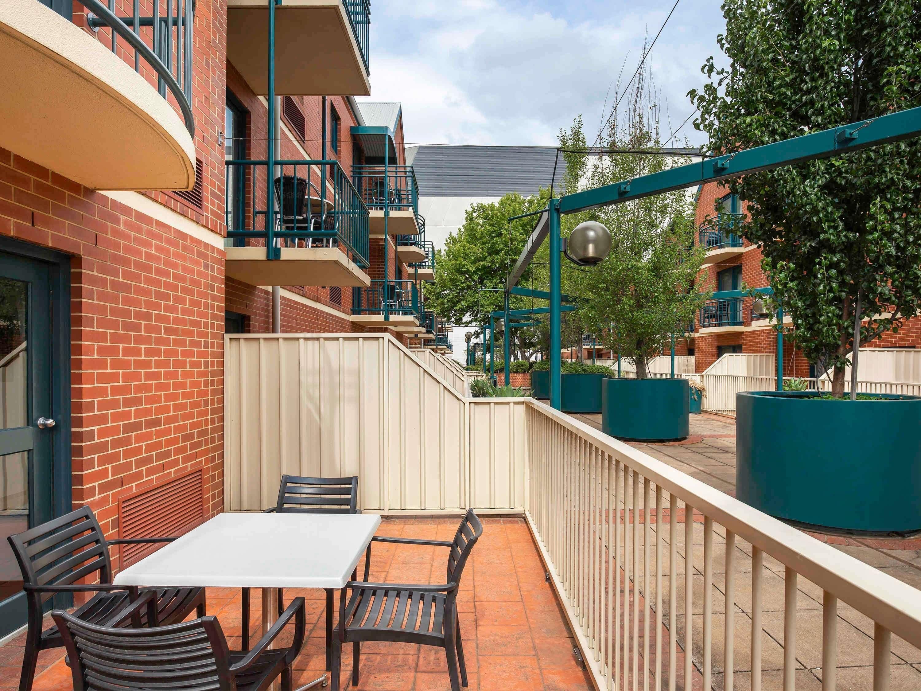 Un patio con una mesa y sillas, una cerca y un edificio con balcones.