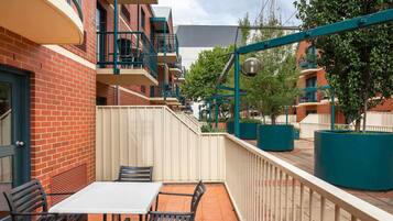 Un patio con una mesa y sillas, una cerca y un edificio con balcones.