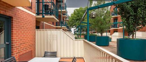 Un patio con una mesa y sillas, una cerca y un edificio con balcones.