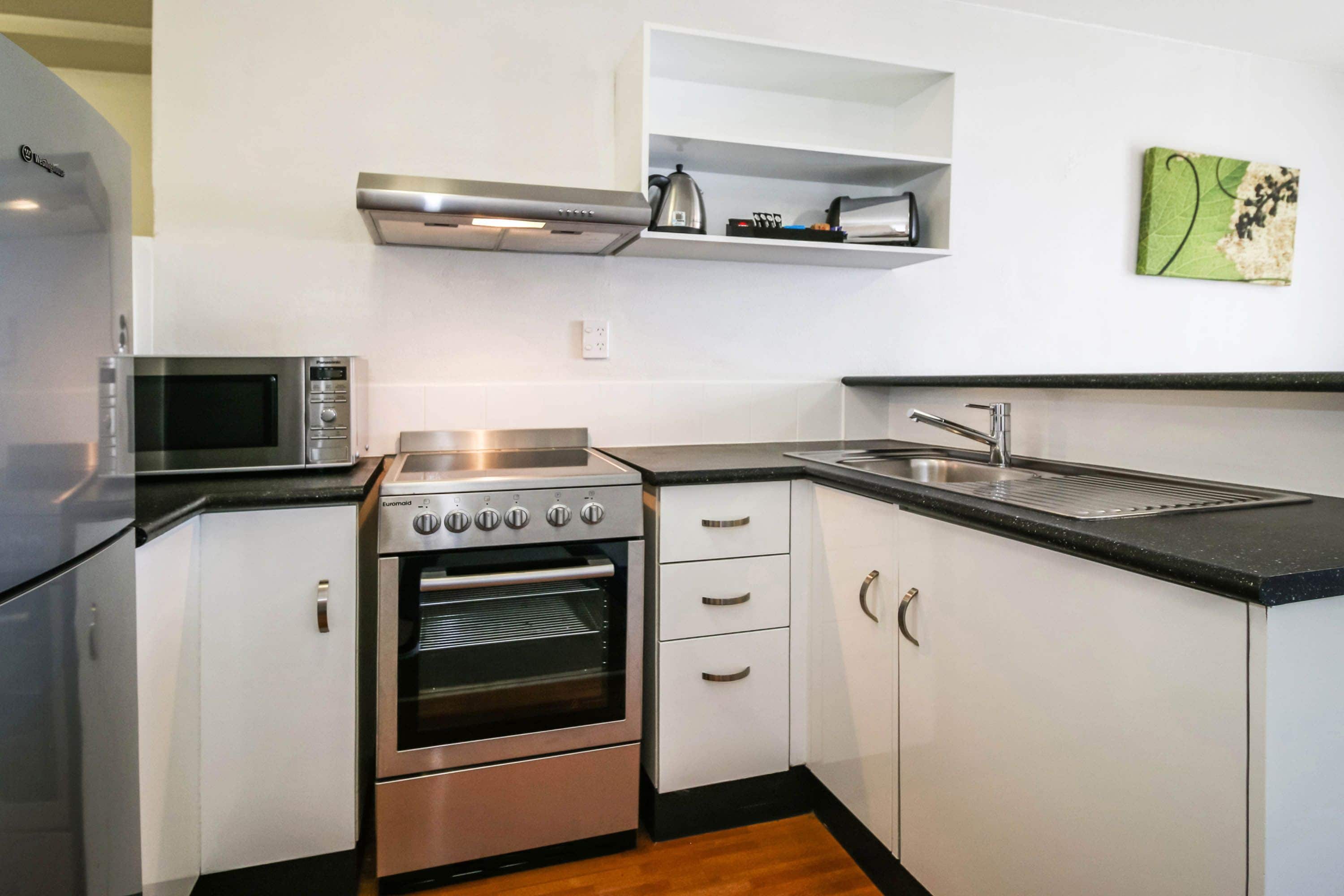 A compact kitchen with a built-in oven, microwave, and stainless steel appliances.