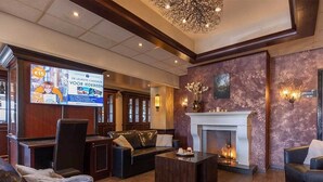A spacious lobby with leather sofas, a fireplace, and a large screen displaying an advertisement.