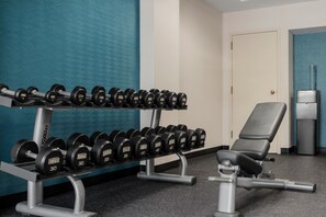 Un gimnasio con una banca, mancuernas y una puerta.