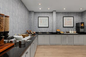 A modern kitchen with grey cabinets, a black countertop, and various food items. - Hyatt Select Nashville/Opryland (Nashville)