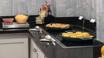Disposição de buffet com diversos alimentos e utensílios de servir.