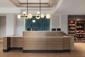 Un mostrador de recepción con diseño moderno, una pantalla montada en la pared y una máquina expendedora de aperitivos al fondo.