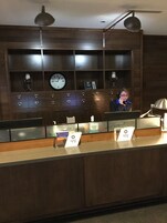 Un mostrador de recepción con un reloj, una copa de vino y un cartel con el logotipo 'spg'.
