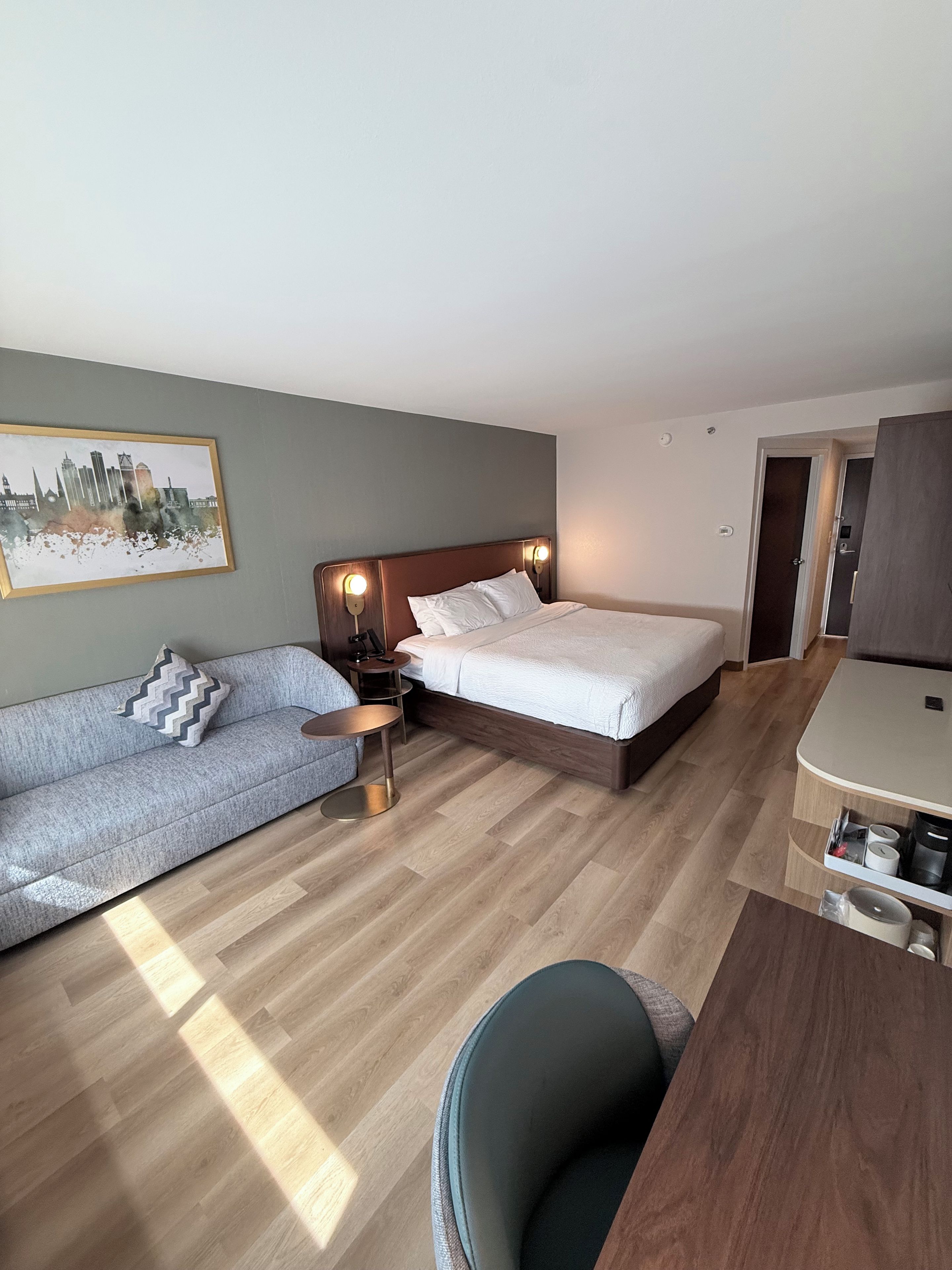 A hotel room with a bed, a sofa, a small table, and a desk.