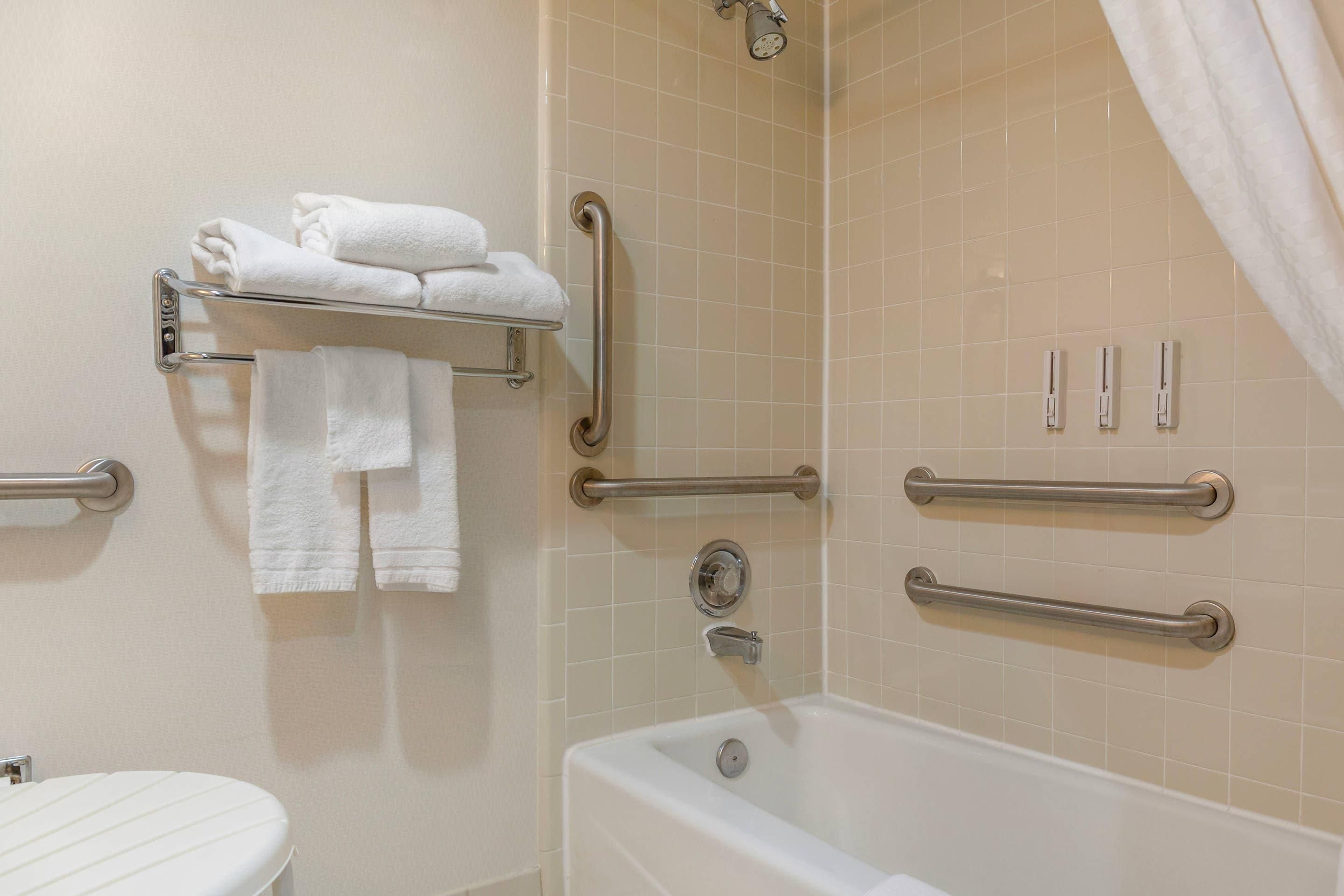 A bathroom with a bathtub, a toilet, and a towel rack with folded towels.