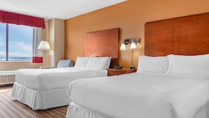 A hotel room with two beds, a wooden headboard, a nightstand with a lamp, and a view of the outdoors. - Radisson Hotel Detroit Metro Airport (Romulus)