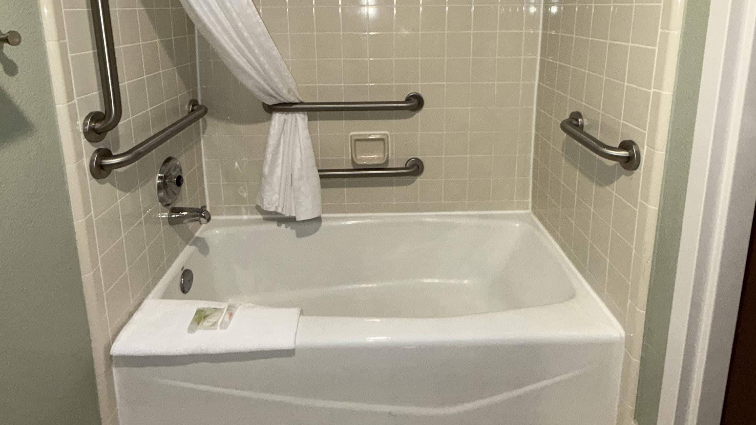 A standard hotel bathroom with a bathtub, grab bars, and a towel rack.