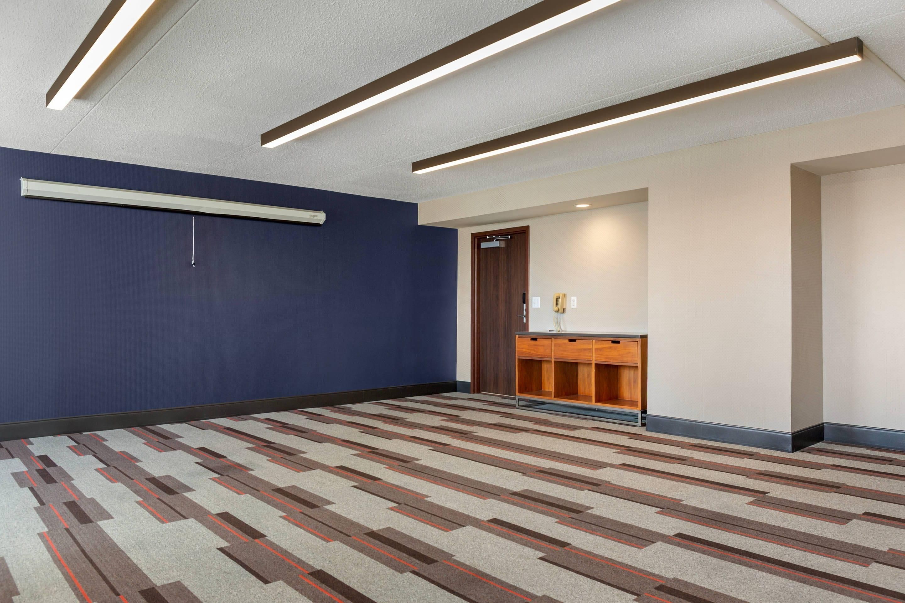 A hotel lobby with a patterned carpet, a reception desk, and a door.