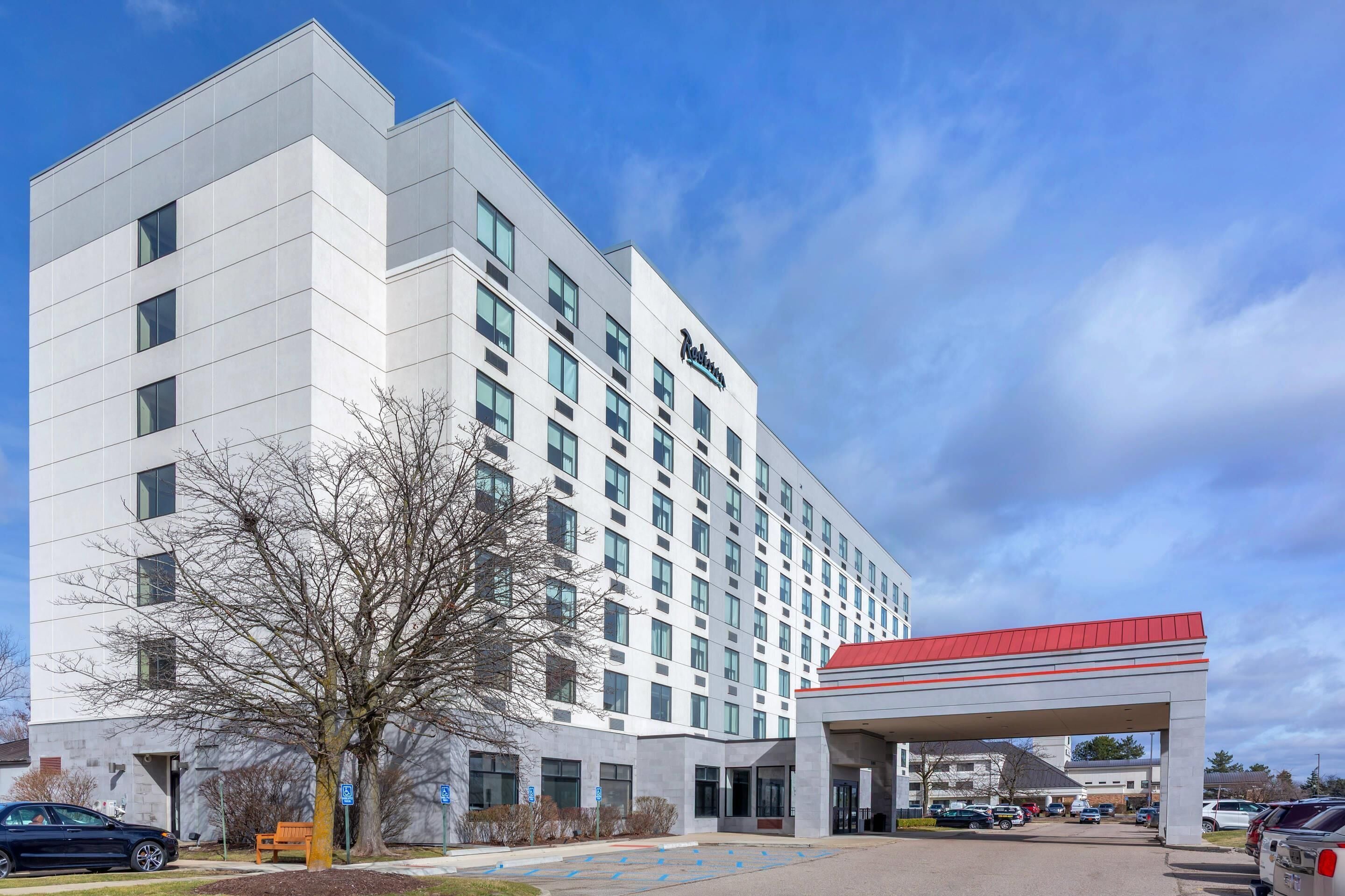 A modern hotel with a flat facade, multiple windows, and a red roof.