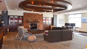 A spacious lobby with a brick fireplace, comfortable seating, and a large screen for presentations. - Radisson Hotel Detroit Metro Airport (Romulus)