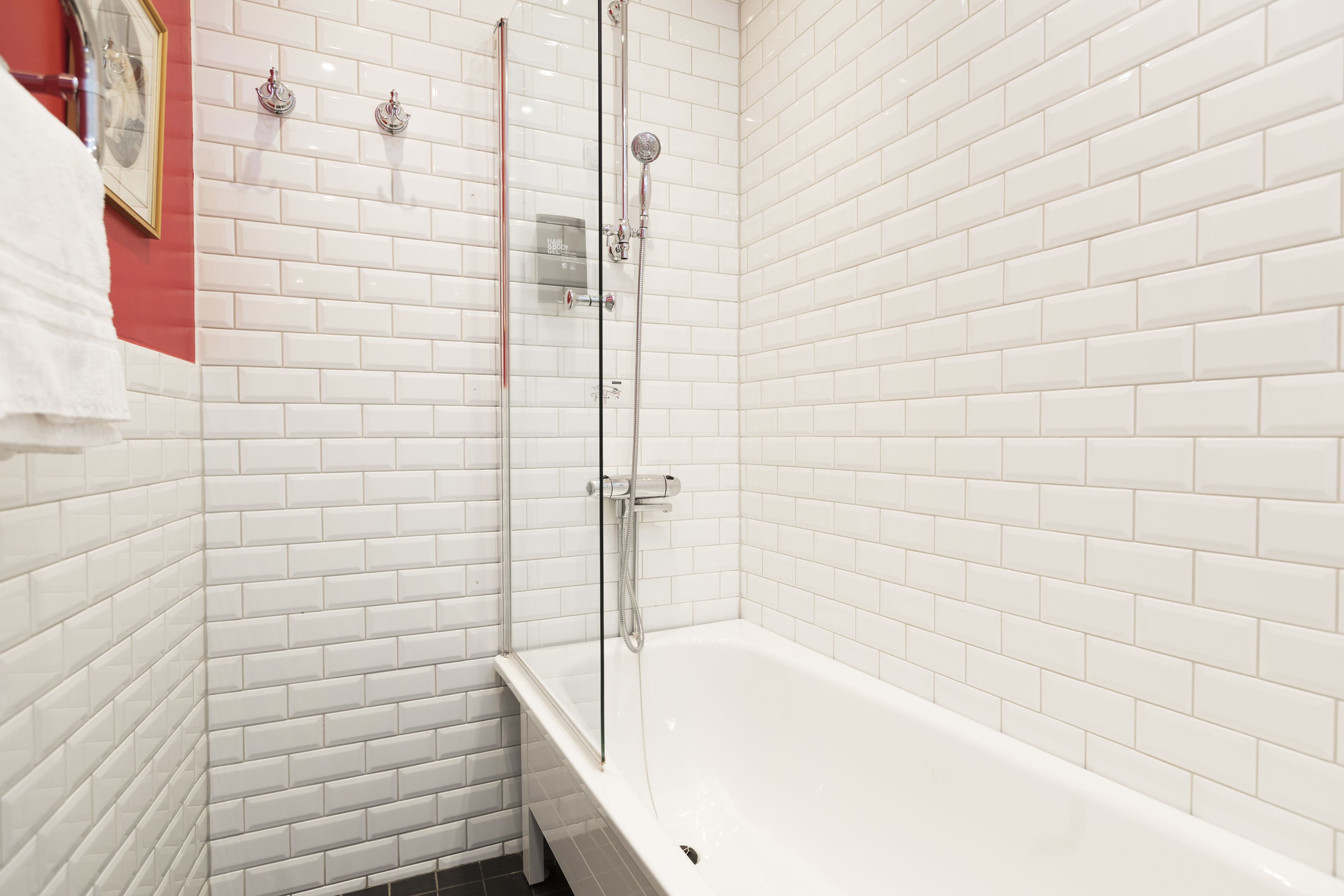 Un bagno moderno con piastrelle bianche tipo metro, una cabina doccia in vetro e una vasca da bagno bianca.