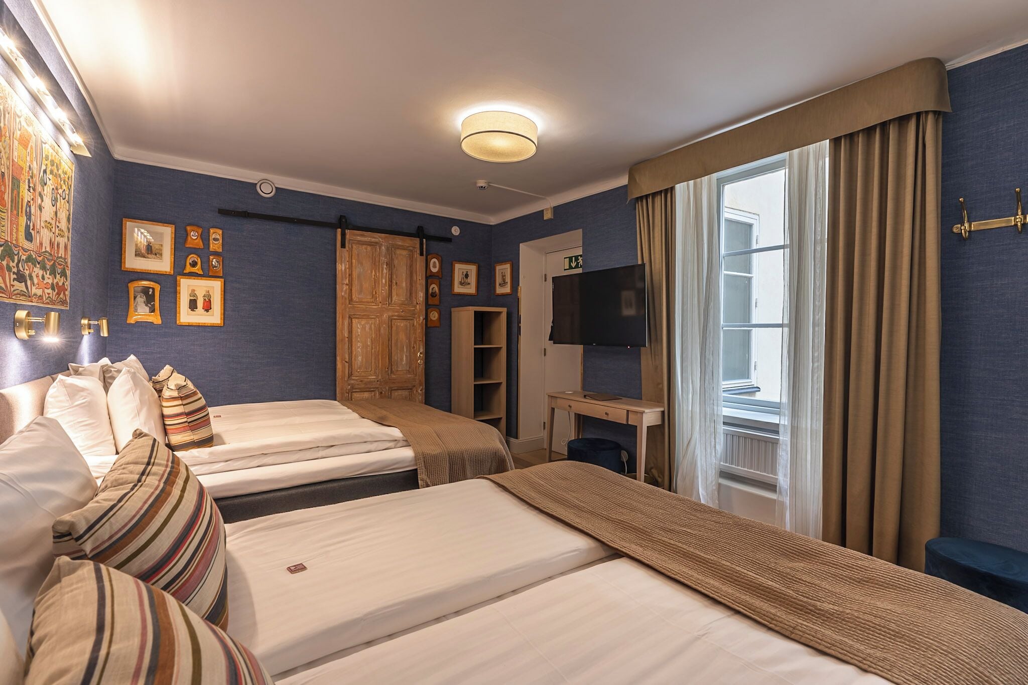 Ett hotellrum med två sängar, ett skrivbord med en tv och en garderob.