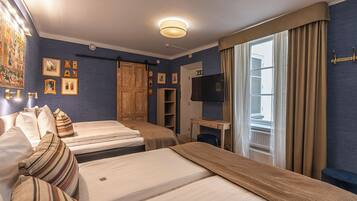 Ett hotellrum med två sängar, ett skrivbord med en tv och en garderob.