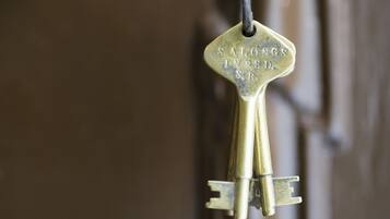 A brass key with the inscription "S. ALONGS IN BED. S.B." hanging on a door handle.