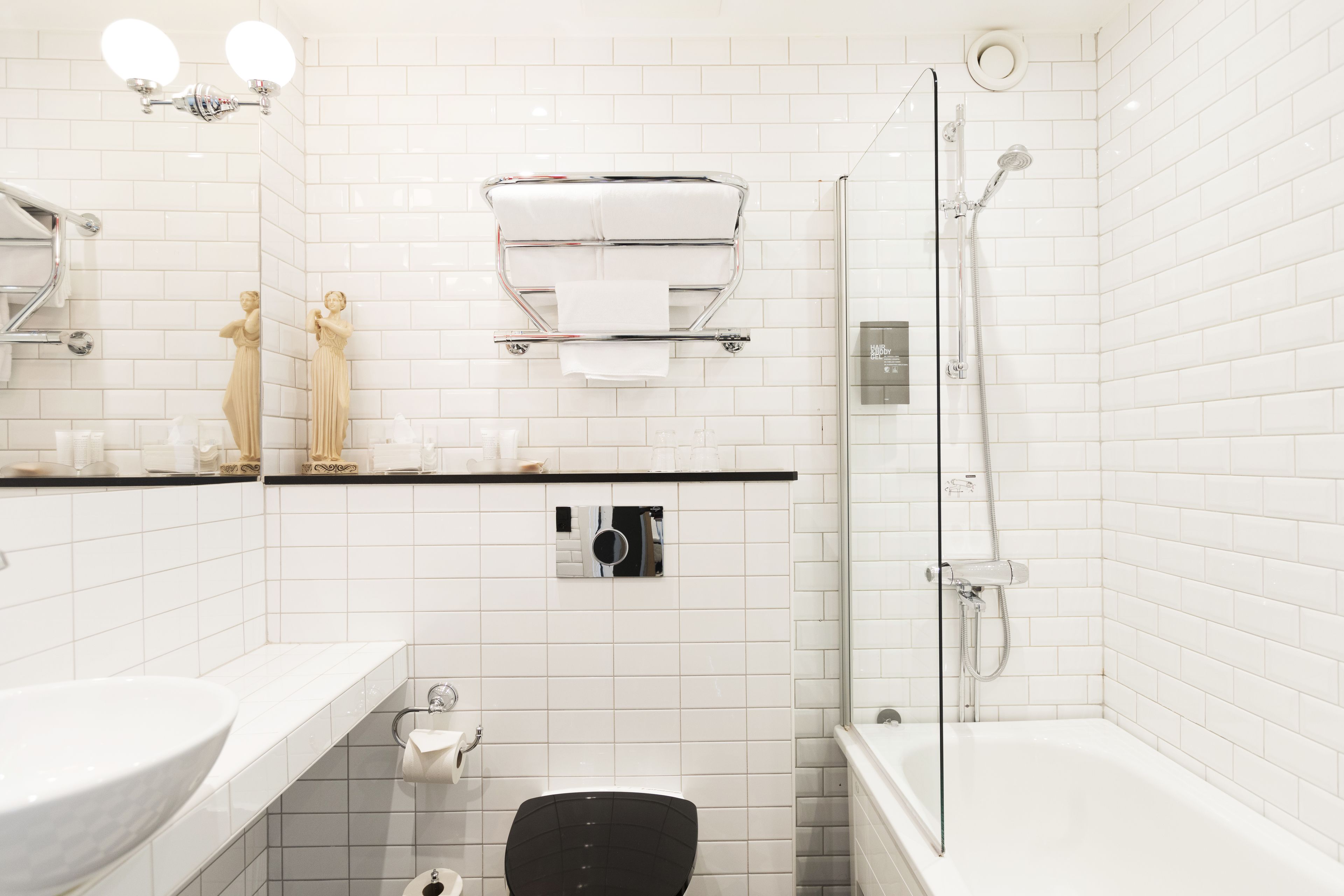 A bathroom with a white sink, toilet, and bathtub. There is a towel rack above the toilet and a showerhead on the right.