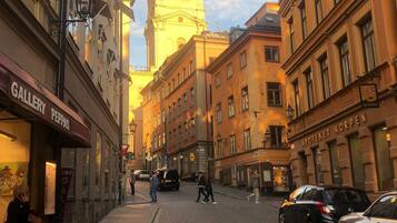 Una calle adoquinada con edificios históricos, una destacada torre del reloj y un hotel llamado "Apoteket Korpen".