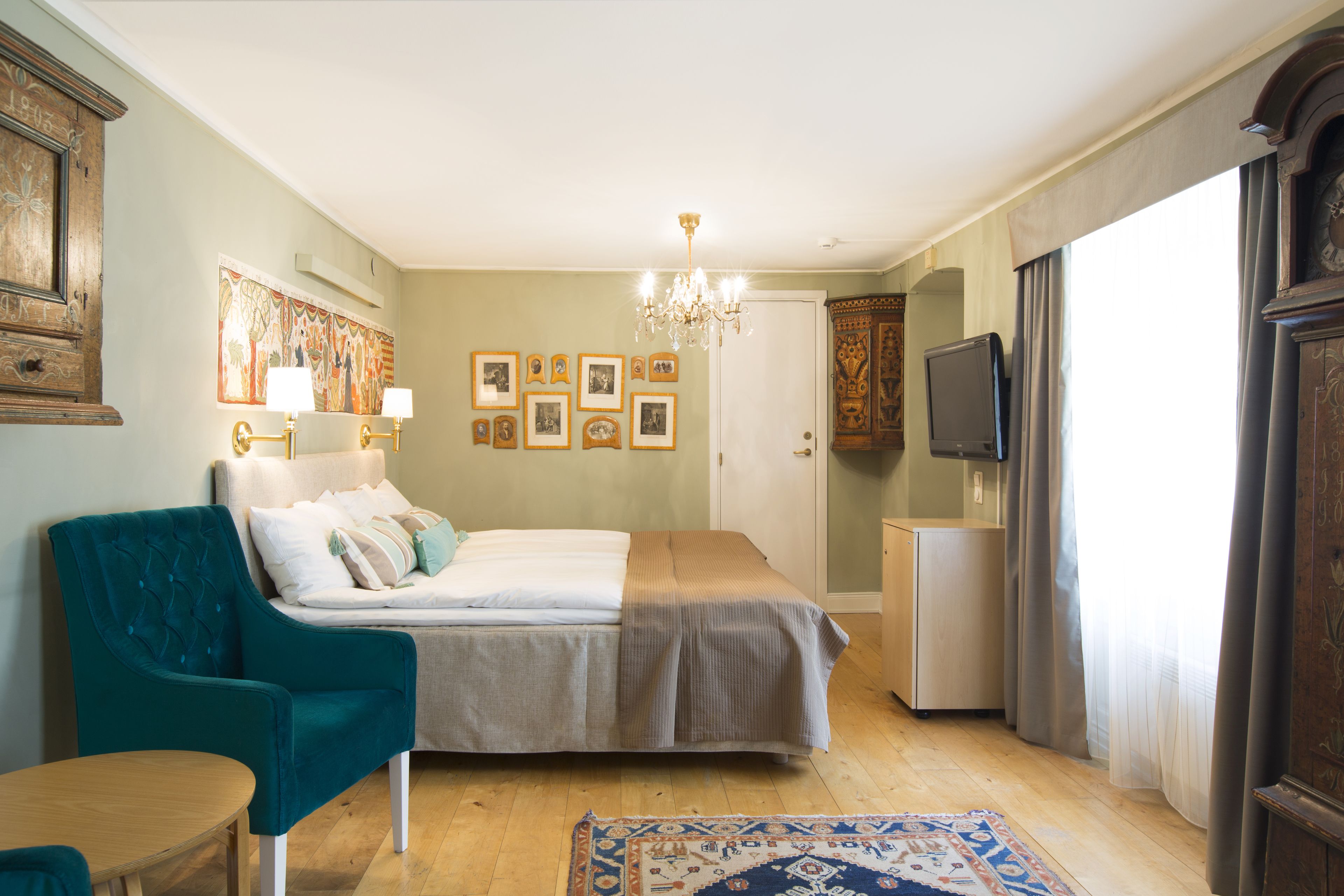 A bedroom with a bed, a chair, a television, and a clock.