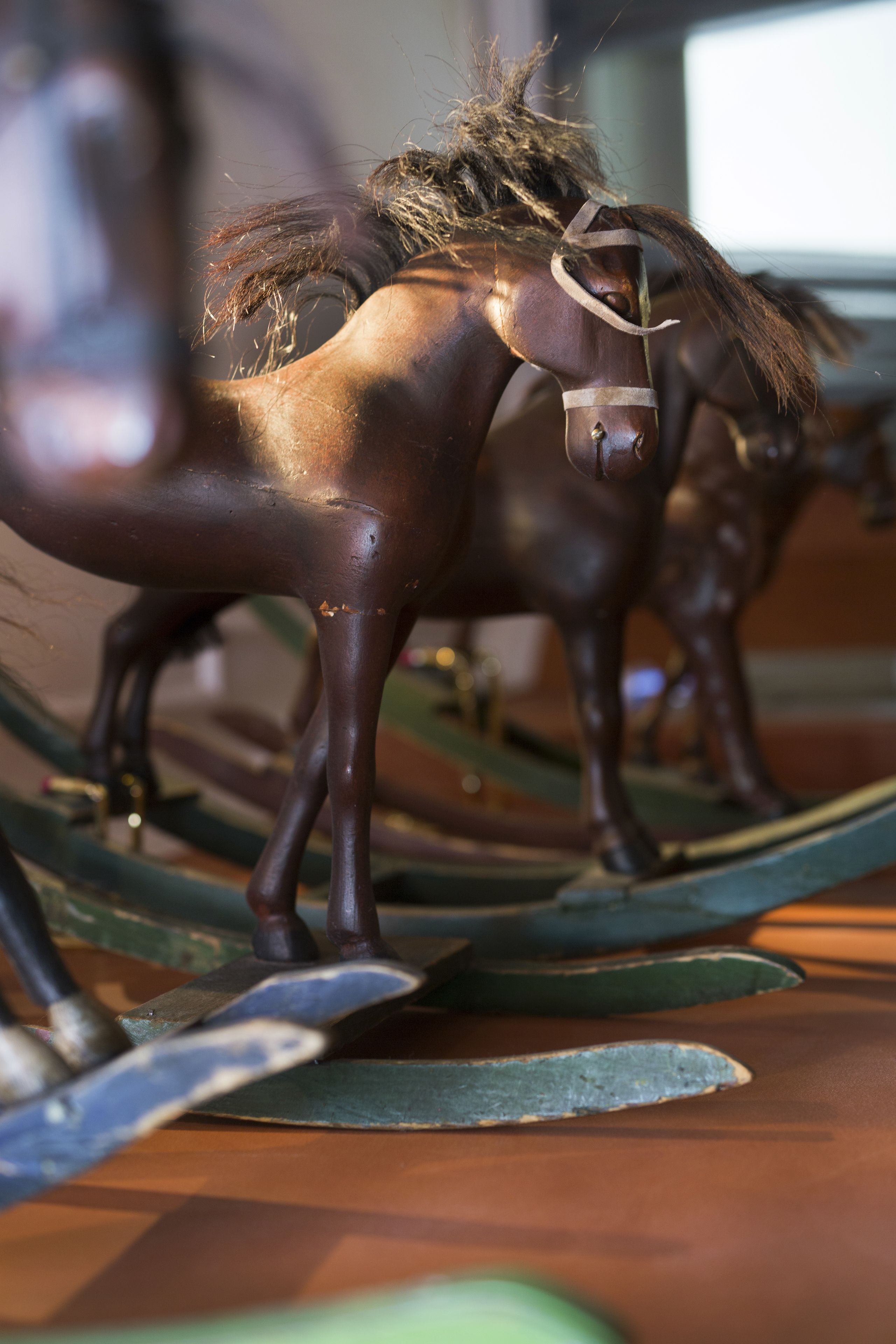 A close-up of a horse sculpture with a metallic finish, positioned on a wooden surface with a blurred background.