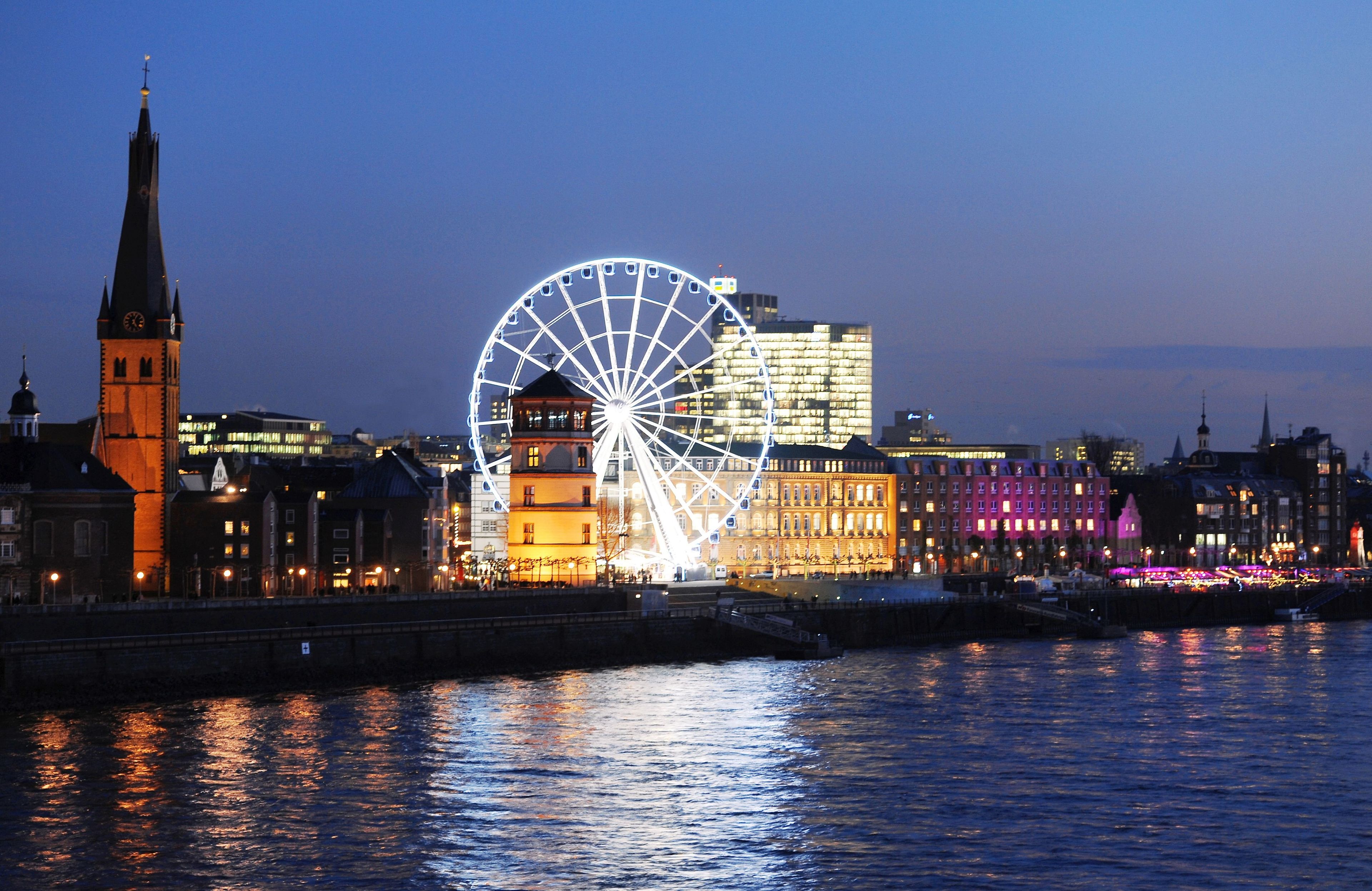 Une vue urbaine avec une grande roue bien visible et une tour de l’horloge.