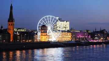 A cityscape with a prominent Ferris wheel and a clock tower.