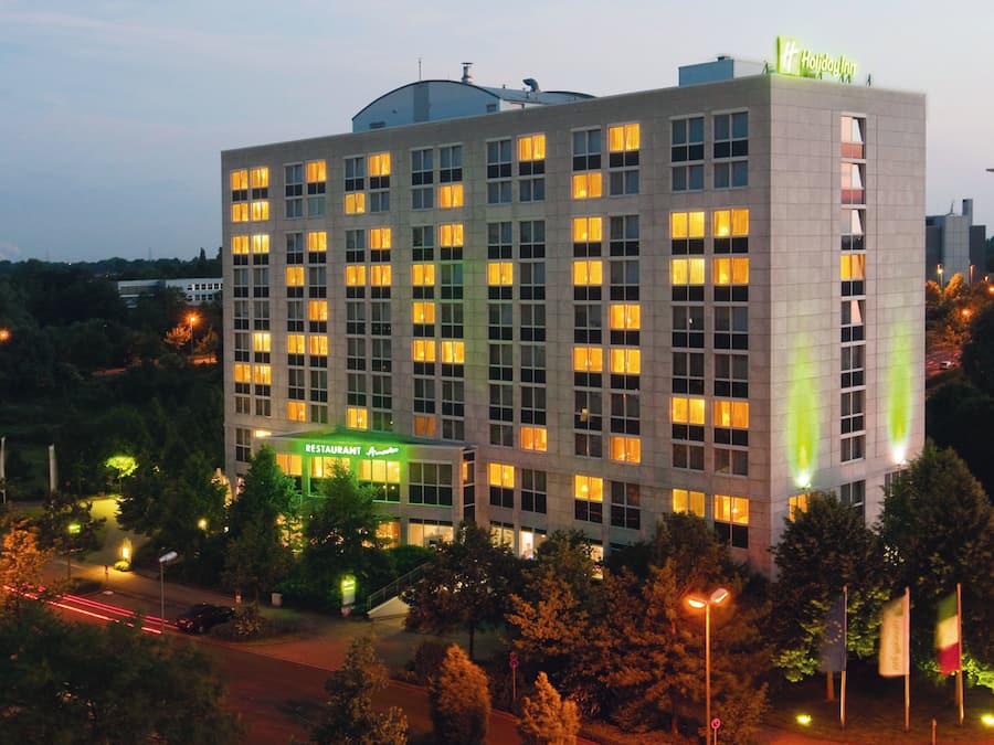 Un hotel de varios pisos con ventanas iluminadas y un letrero llamativo para un restaurante.