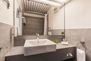 Un baño moderno con un lavamanos grande, espejo y zona de ducha.