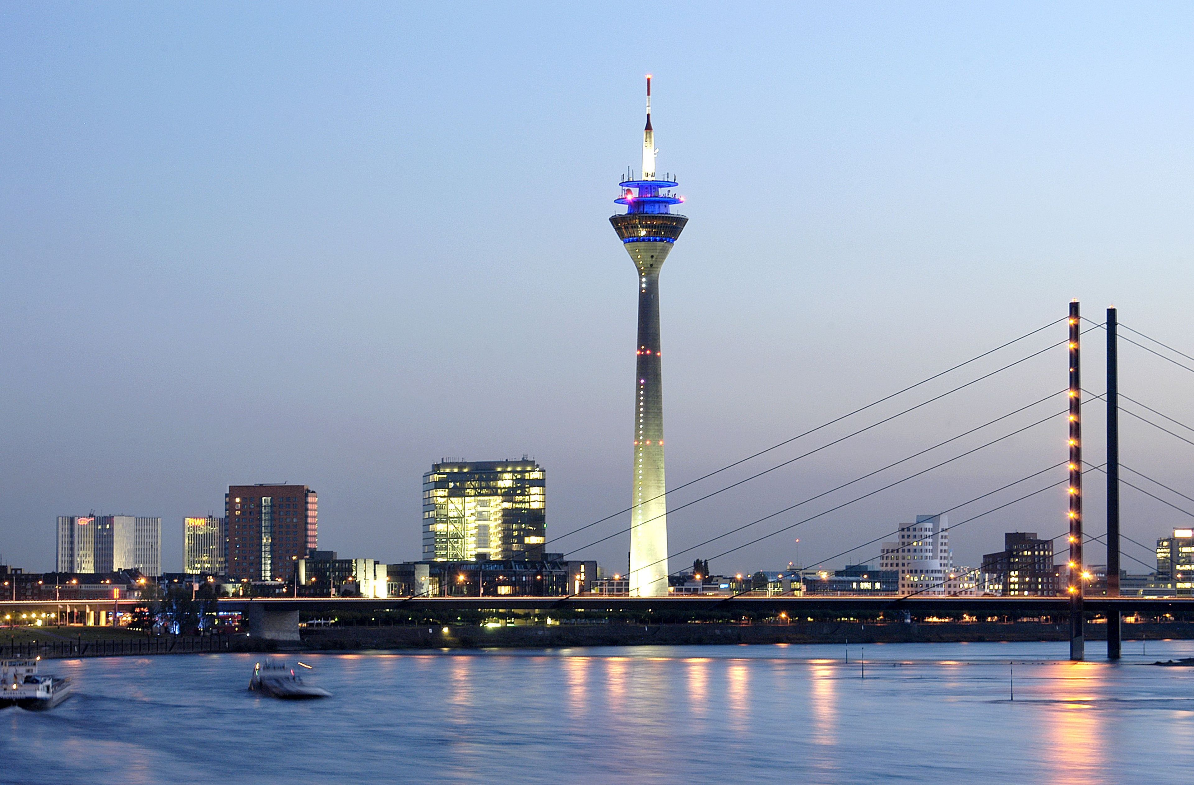 A city skyline with a prominent tower and a bridge.