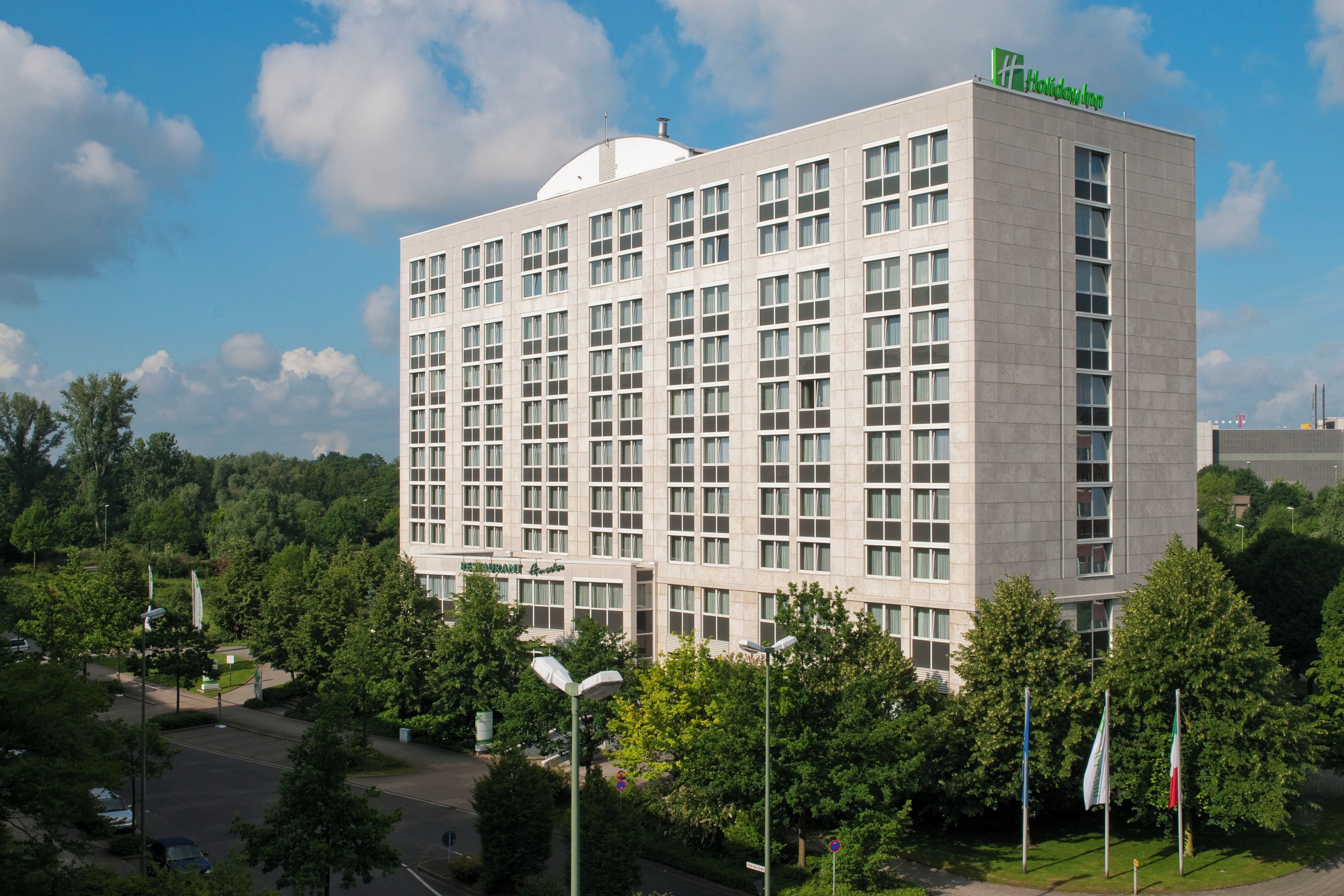 Ein großes, mehrstöckiges Holiday Inn Hotel mit flachem Dach und einem auffälligen grünen Logo oben.